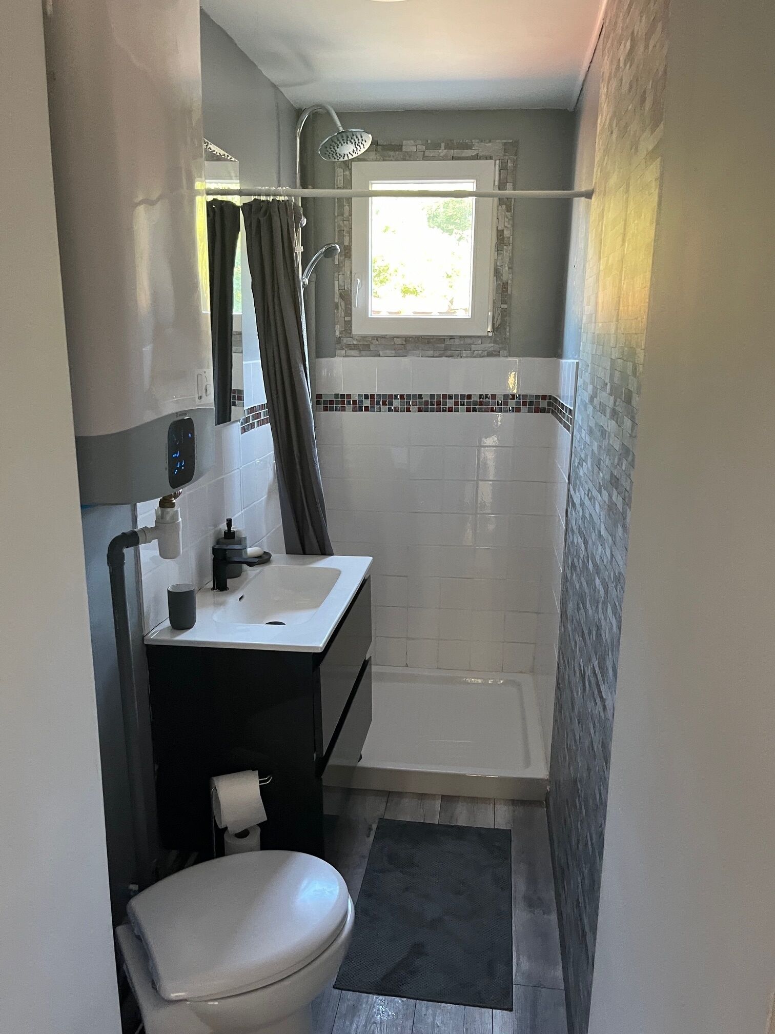 A compact bathroom with a toilet, sink, and shower.