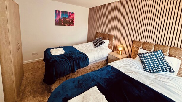 Ein modernes Hotelzimmer mit zwei Betten, einem Lattenrost-Kopfstück, einer Neonreklame und einem Stadtbild an der Wand.