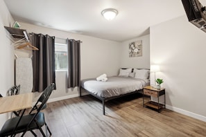 A bedroom with a bed, bedside table, lamp, and a window with curtains. - Judkins Entire Home Near Downtown & Light Rail (Seattle)