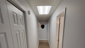 A narrow hallway with wooden flooring, white walls, and doors on both sides.