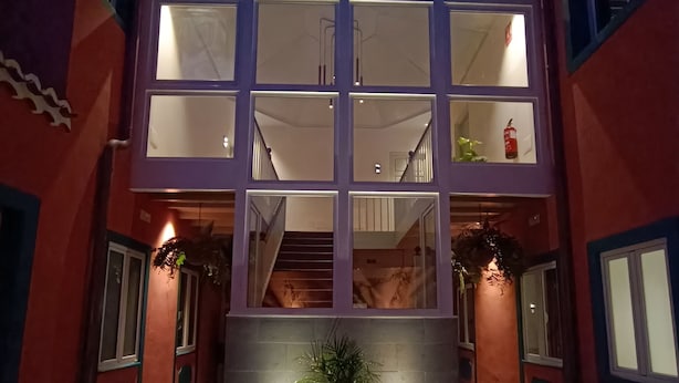 A building with a central staircase, large windows, and a potted plant in the entrance.