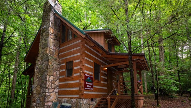 Eine Blockhütte mit Stein Fundament, einer Holzterrasse und einem Schild, das anzeigt, dass sie zum Wildwood Inn Emerald Pines gehört.