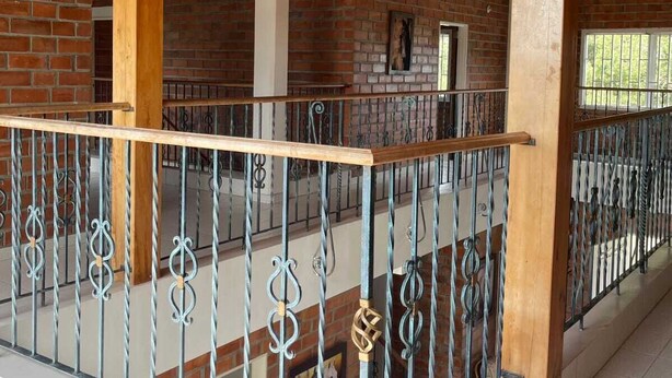 A covered outdoor area with a wooden ceiling, brick walls, and a metal railing. - 2-story country farm in Guarne (Guarne)