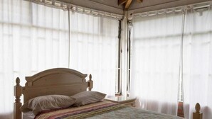 A bedroom with a wooden bed, white curtains, and a tiled floor. - 2-story country farm in Guarne (Guarne)