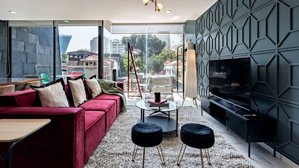 A modern living room with a red sofa, black ottomans, a glass coffee table, and a large TV on a black stand. - Bright, Stylish Retreat w/ Private Balcony & WiFi (Ciudad de México)