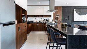 A modern kitchen with a central island, stainless steel appliances, and a large abstract painting on the wall. - Bright, Stylish Retreat w/ Private Balcony & WiFi (Ciudad de México)