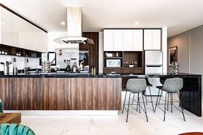 A modern kitchen with a central island, bar stools, and a dining area.