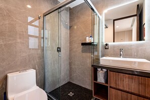 A modern bathroom with a glass-enclosed shower, a white bathtub, and a wooden vanity with a mirror.