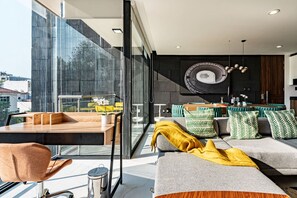 A modern living space with a glass wall, a dining area, and a kitchen.