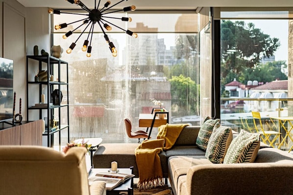 A modern living room with a large window, a unique ceiling light, and a view of the city.