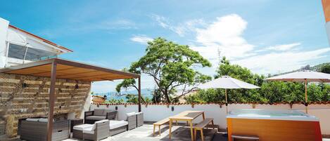 Un patio con mobiliario exterior, un jacuzzi y vista al mar.