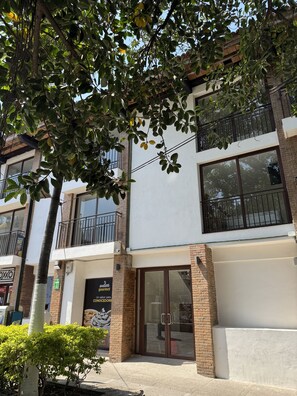 Un edificio de varios pisos con entrada a nivel de calle, ventanas amplias y un balcón.