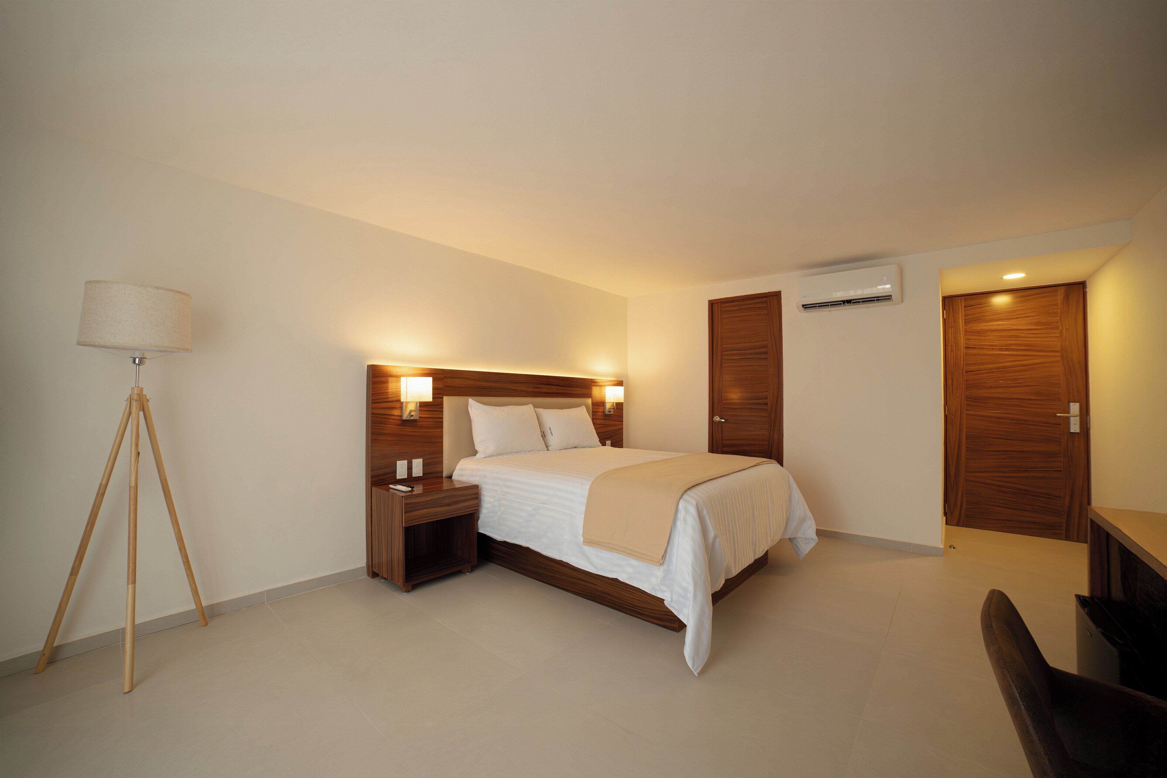 A modern bedroom with a bed, bedside tables, a lamp, and a desk.