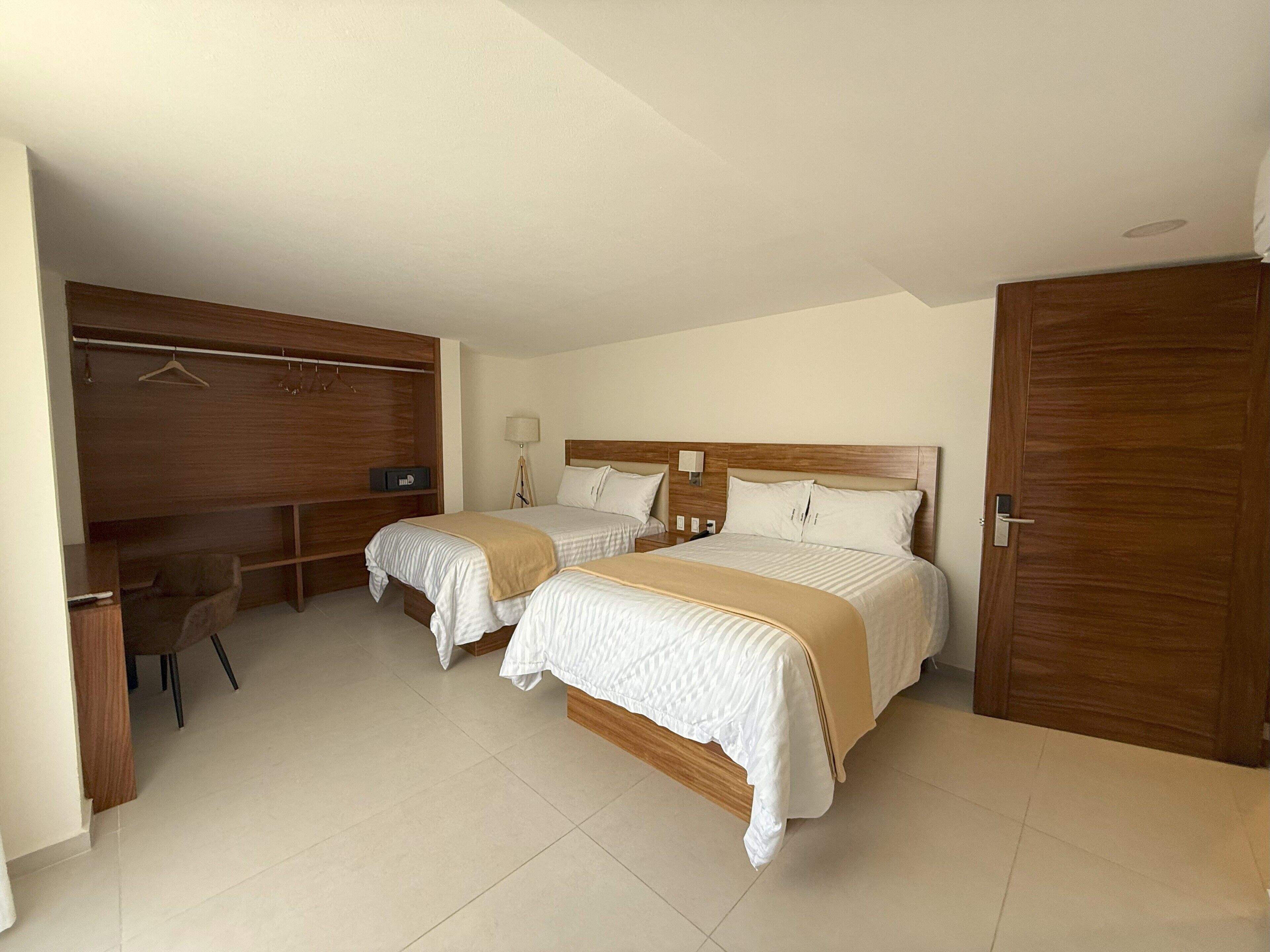 Un dormitorio con dos camas, un armario de madera, un escritorio y una silla.