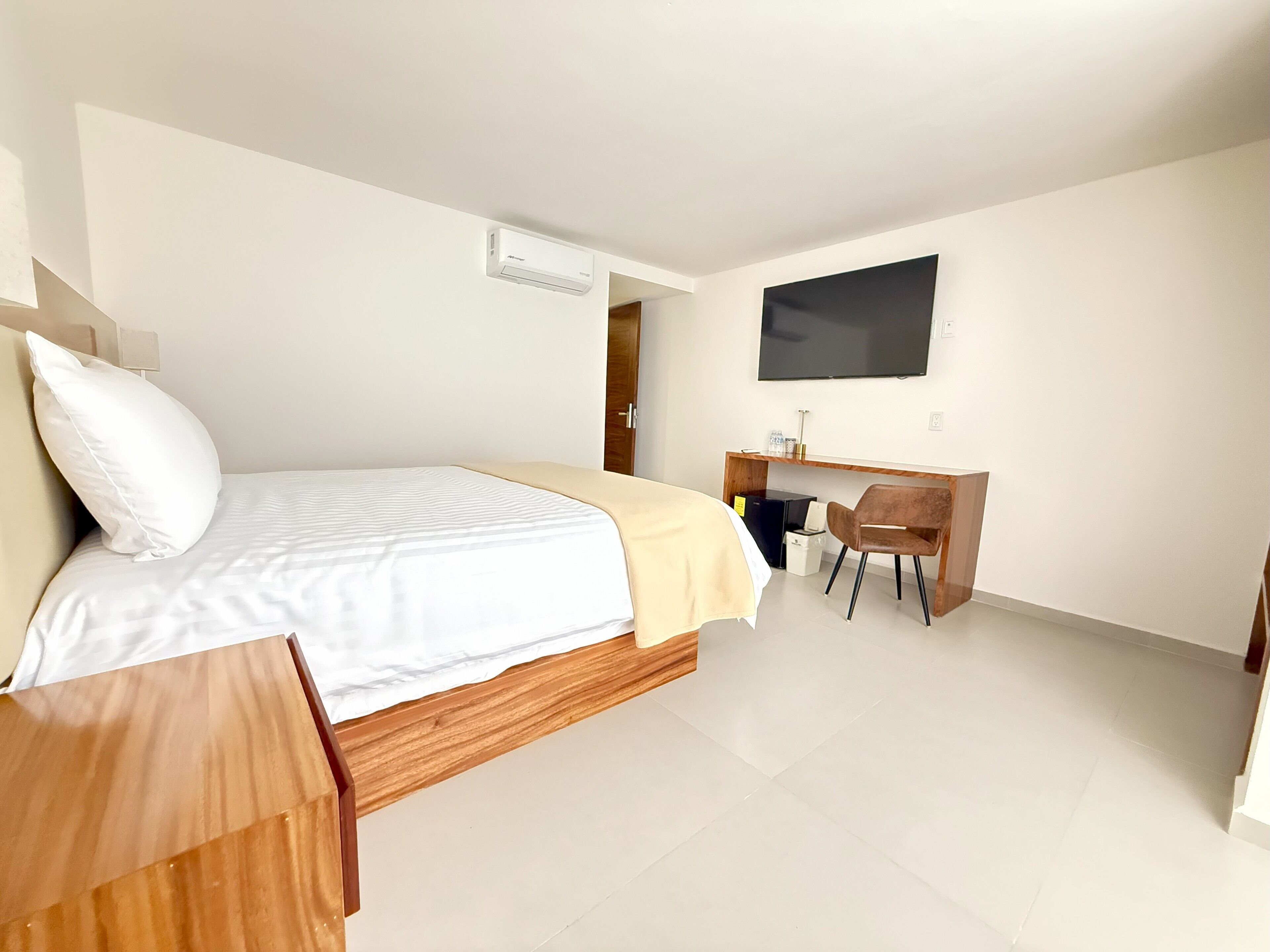 Une chambre d’hôtel avec un lit, un bureau, une chaise, une télévision et une fenêtre.