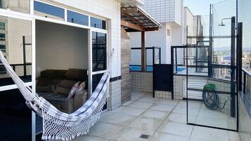 Un balcón con hamaca, sofá y vista a la piscina.