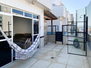 A balcony with a hammock, a sofa, and a pool view. - Ático con piscina - Guarapari (Guarapari)