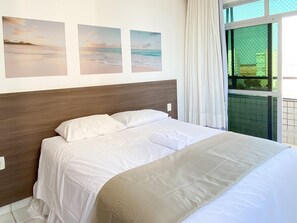 A neatly made bed with white linens and a beige throw blanket, a wooden headboard, and three beach scene paintings on the wall. - Ático con piscina - Guarapari (Guarapari)