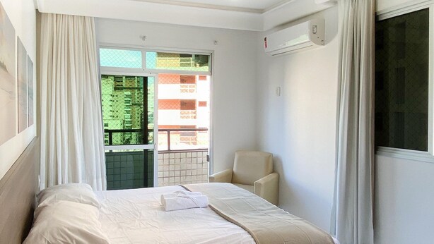 A hotel room with a bed, a chair, and a window with curtains. - Ático con piscina - Guarapari (Guarapari)