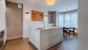 A modern kitchen with white cabinetry, a central island with a sink, and artwork on the wall.
