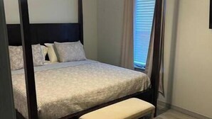 A four-poster bed with a bench, a ceiling fan, and a window with curtains. - Hidden gem (Blanchard)