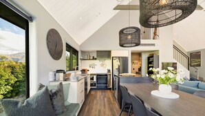 A modern kitchen with a large island, a dining area with a sofa, and a view of the outdoors.