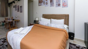 A neatly made bed with a brown headboard, a small table with a lamp, and a chair.
