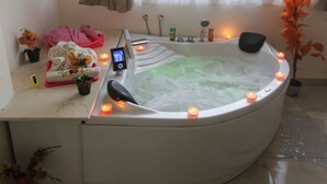 A modern bathroom with a freestanding bathtub, candles, a digital control panel, and towels.