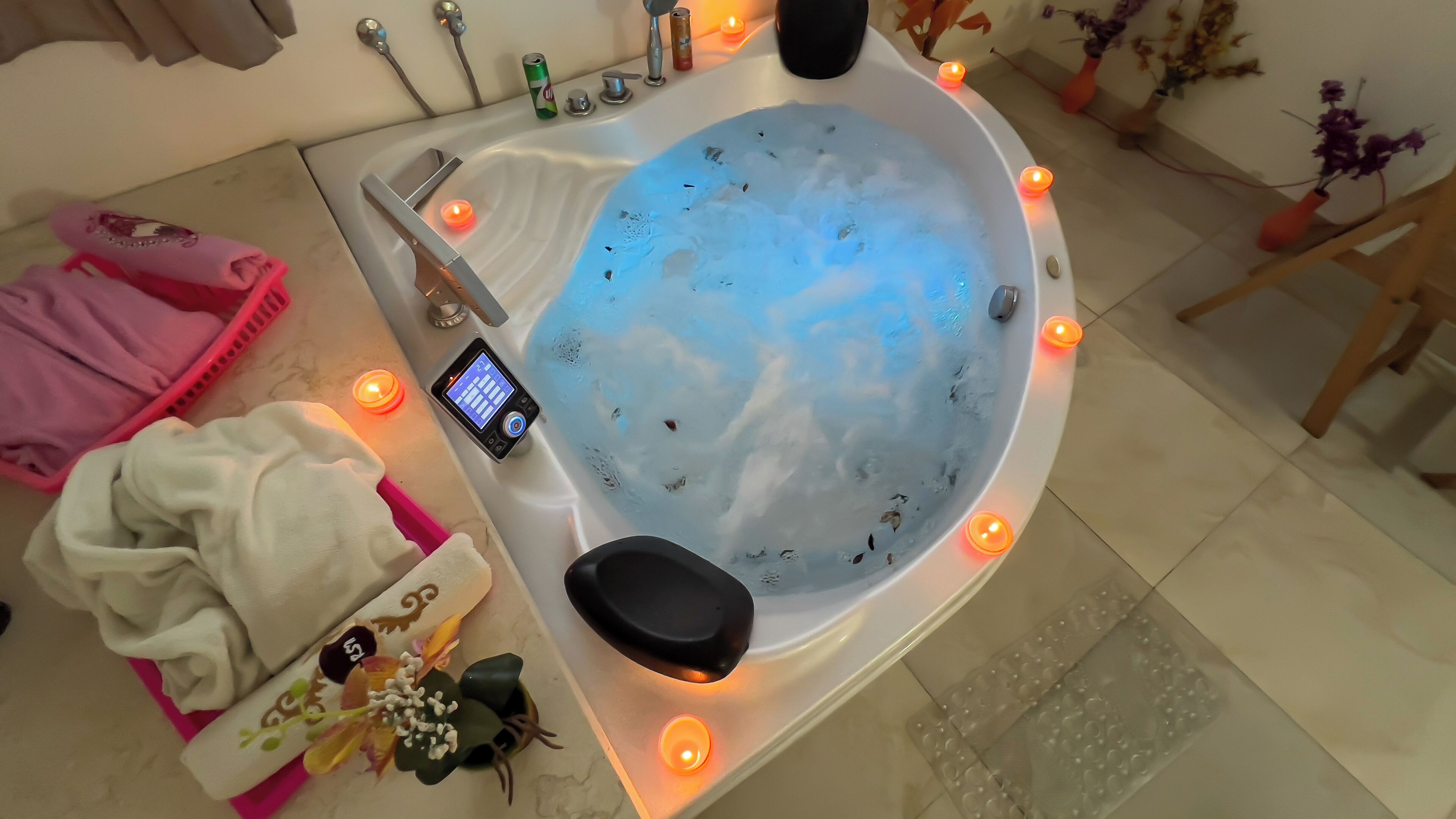 A modern bathroom with a freestanding bathtub, a digital control panel, and multiple candles for ambiance.