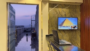 A hotel lobby with a marble wall, a television displaying a pyramid, and a laptop on a counter. - Luxury jacuzzi & pyramids view  (Giza)