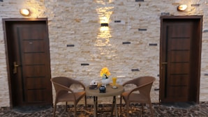 A room with a stone wall, two wooden doors, a round table with chairs, and a vase with flowers. - Luxury jacuzzi & pyramids view  (Giza)
