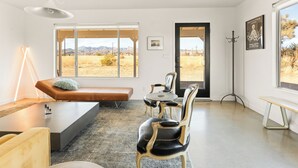 Un salon moderne avec une grande fenêtre, un canapé, une table à manger et une table basse.