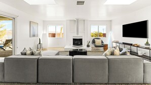 Un salon moderne avec un grand canapé d’angle gris, une cheminée et un téléviseur à écran plat.