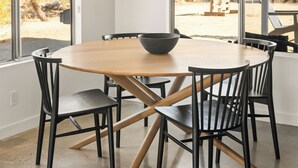 Un espace repas avec une table ronde, des chaises noires et un luminaire suspendu.