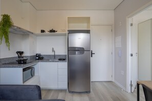 A compact kitchen with a built-in refrigerator, microwave, and a small countertop with a coffee maker. - AD330 (São Paulo)