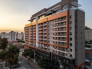 A multi-story residential building with balconies, a parking garage below, and a clear view of the surrounding cityscape. - AD330 (São Paulo)