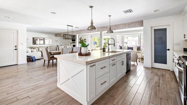 A spacious kitchen with a large island, modern pendant lights, and a view into the dining area.