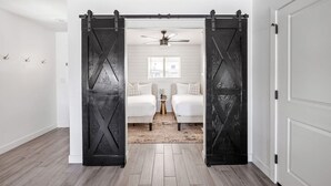 A room with a bed, a small table, and a ceiling fan.