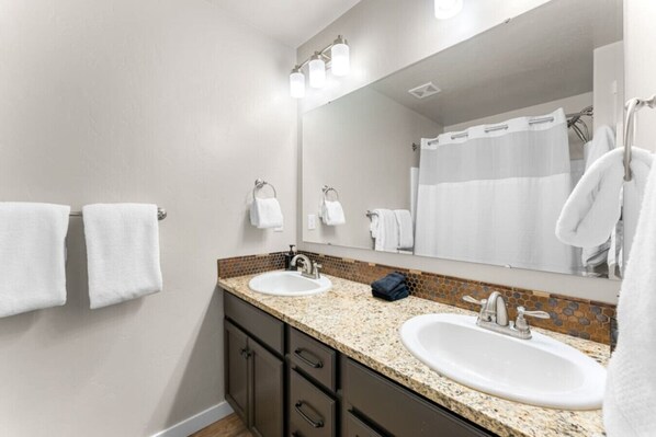 A bathroom with two sinks, a large mirror, and a shower curtain.