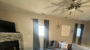 A living room with a fireplace, a ceiling fan, a sofa, and a coffee table. - Prime Location In Lewes-  3bed/2bath Great space and game room. (Lewes)