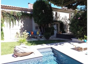 A pool area with a small pool, outdoor seating, and a pergola with climbing plants. - Charming, quiet T1 (Saint-Andiol)