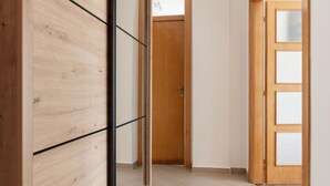 A hallway with wooden flooring, a wooden door with glass panels, and a sliding wooden door. - Stylish Budva Apt withPanoramic View-2Bedroom Apt (Budva)
