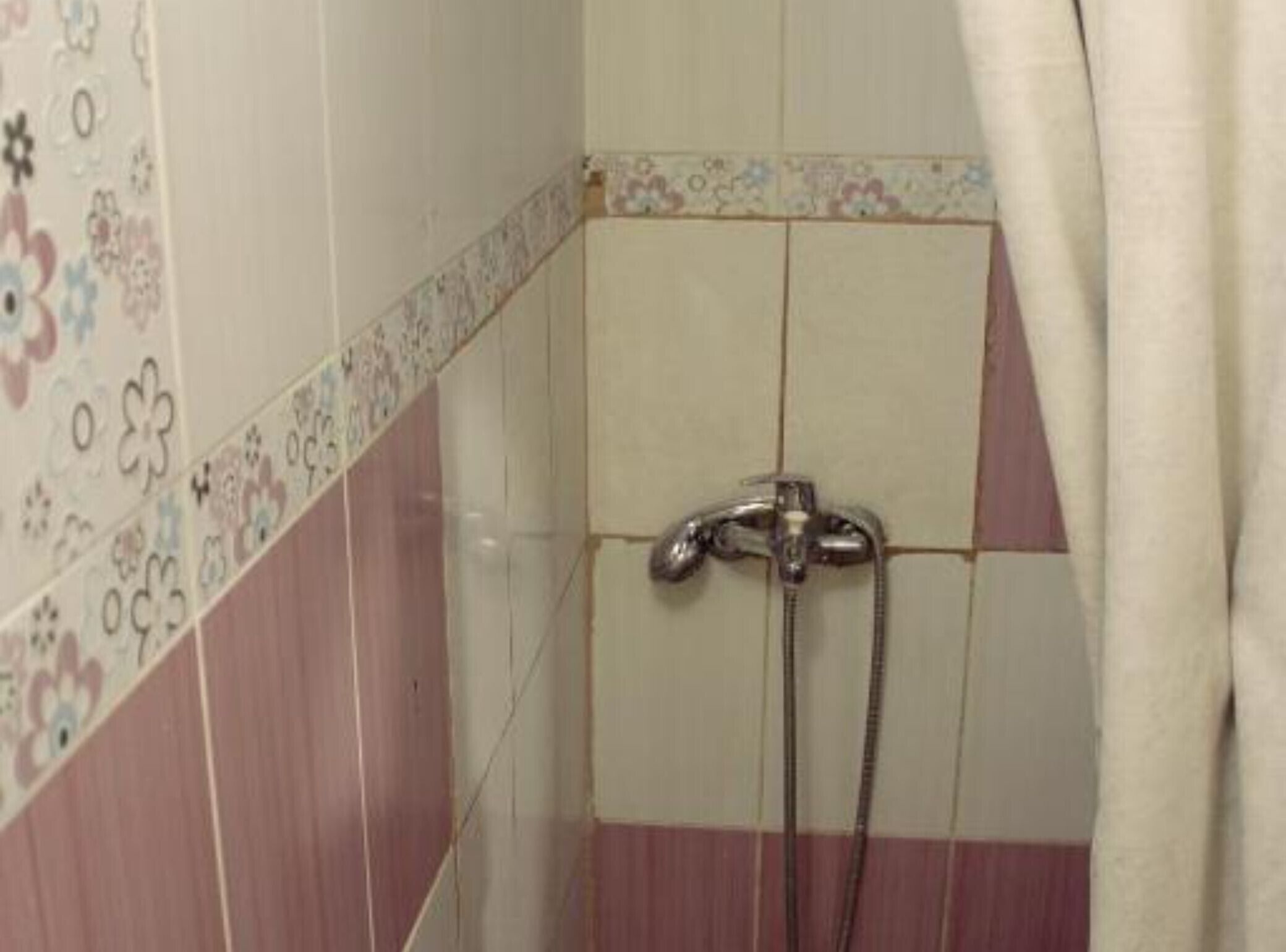 A bathroom with a shower, tiled walls, and a decorative border.