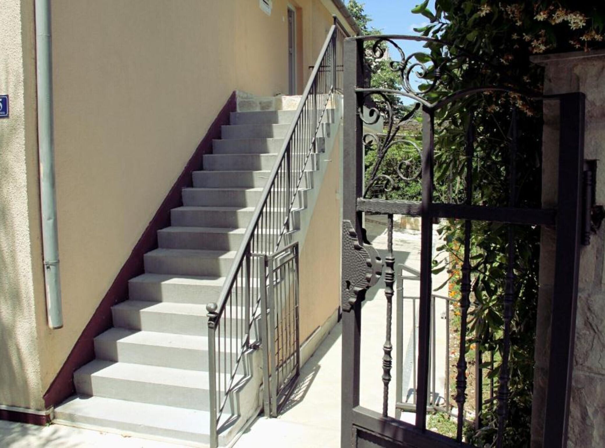 Un escalier avec une rampe métallique menant à l’entrée d’un bâtiment.