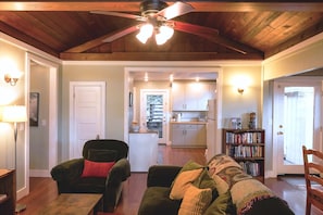 A cozy living room with a ceiling fan, a fireplace, and a bookshelf.