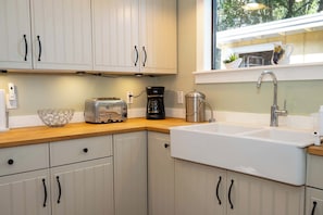 A kitchen with white cabinets, a wooden countertop, a toaster, a coffee maker, and a sink.
