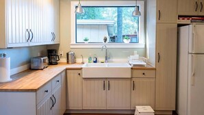 Una cocina moderna con armarios de madera clara, un ventanal grande e iluminación colgante.