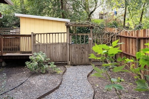 A wooden gate leading to a yellow building, surrounded by a gravel path and greenery. - Riverbend Retreat - Hot Tub and Tastings Included (Healdsburg)