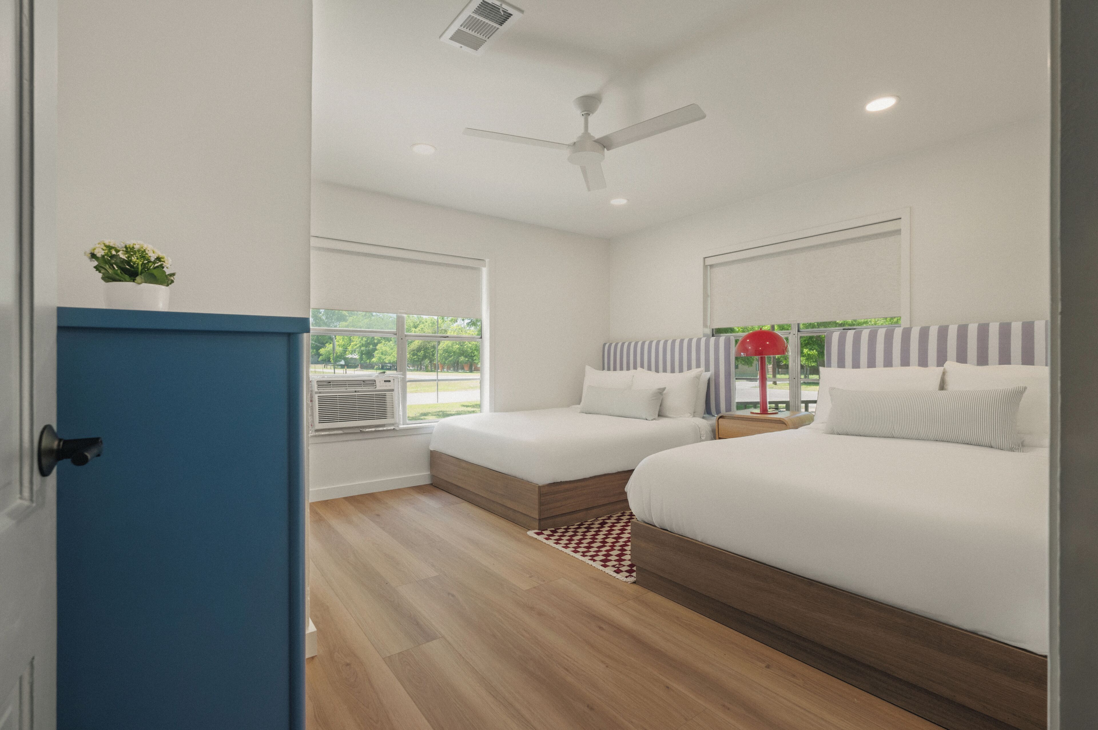 A bedroom with two beds, a ceiling fan, and a window.