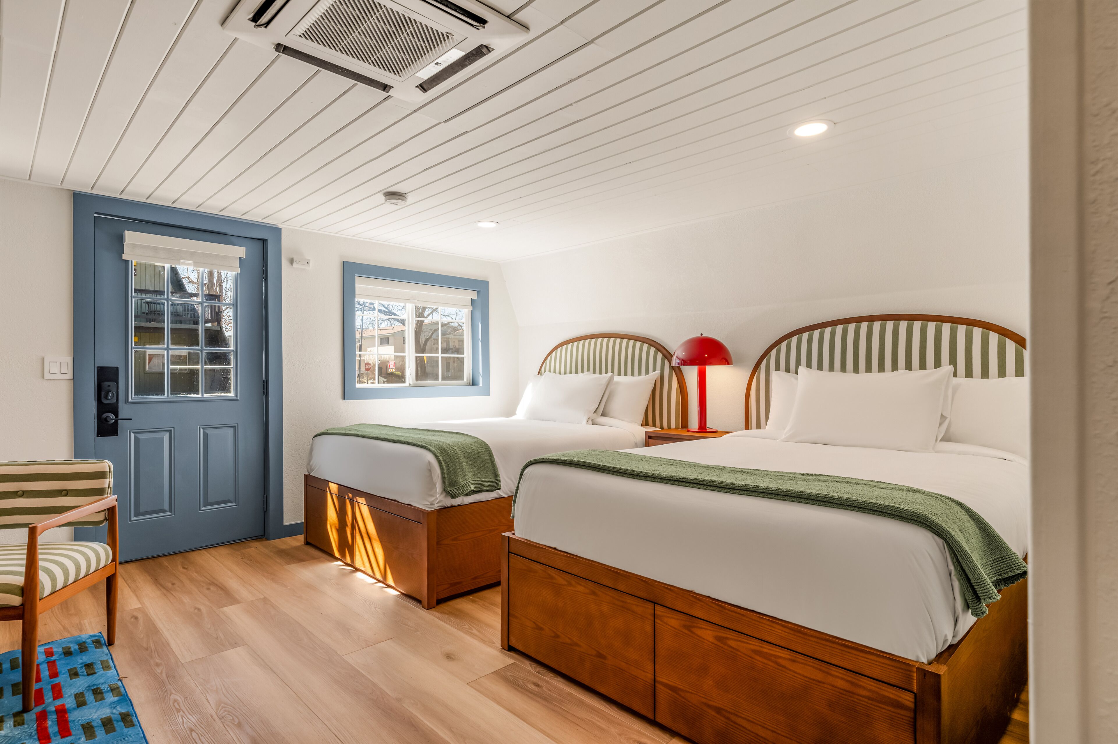 Une chambre avec deux lits, une fenêtre, une porte et une chaise.